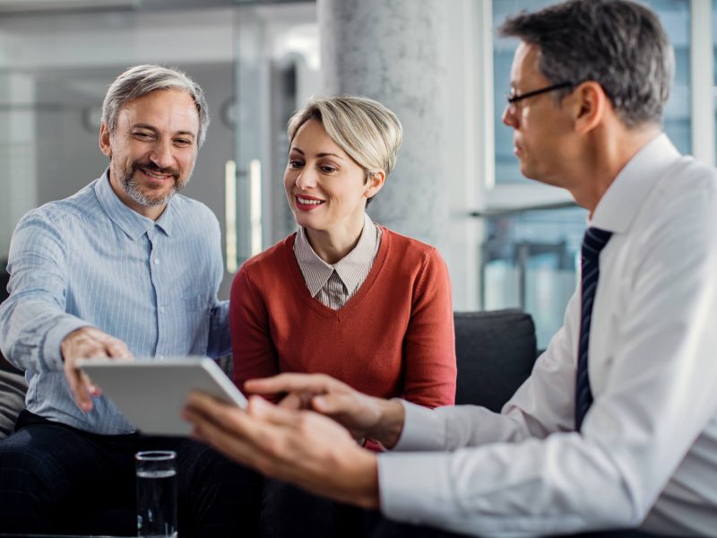 happy-mid-adult-couple-using-touchpad-with-their-financial-consultant-in-the-office-.jpg